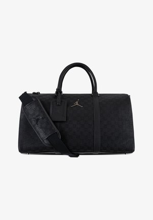 Sac de sport noir avec un motif en relief à carreaux, des poignées en cuir et une bandoulière amovible. Détails notables avec le logo Jumpman.