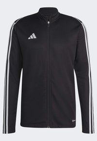 Chaqueta deportiva negra hecha de tela suave con cremallera completa. Presenta tres rayas blancas en cada manga y un pequeño logo en la parte superior izquierda.