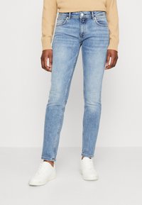 Ljust blå denimjeans med slim fit, som har traditionell femficksdesign och subtila slitningar på låren.