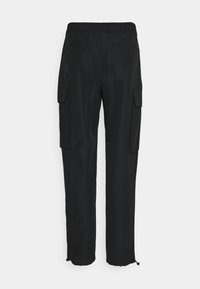 Pantalon cargo noir avec poches latérales à rabat et cordons ajustables à la cheville, montré de dos sur fond blanc.