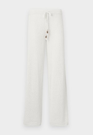 Pantalones de lounge blancos de punto con un patrón texturizado, que cuentan con una cinturilla con cordón y dos botones decorativos en la parte frontal.