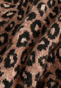 Tissu tricoté présentant un motif léopard avec de grandes taches noires sur un fond rose clair doux. Aspect texturé et chaleureux.