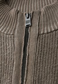 Pull en maille beige à zip, avec une texture côtelée, doté d'un zip noir et d'une tirette métallique étiquetée "Street One Men."