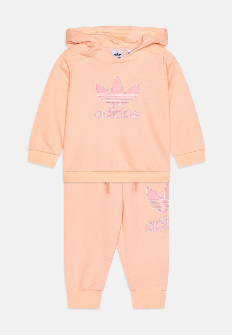 Set de hanorac și pantaloni de trening în culoarea piersicii, din material din bumbac, având un logo „adidas” brodat și un design cu trefoil pe ambele piese.