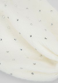 Sciarpa bianca lavorata a maglia con motivo a diamante testurizzato, decorata con piccoli borchiette d'argento che creano un effetto decorativo sottile.