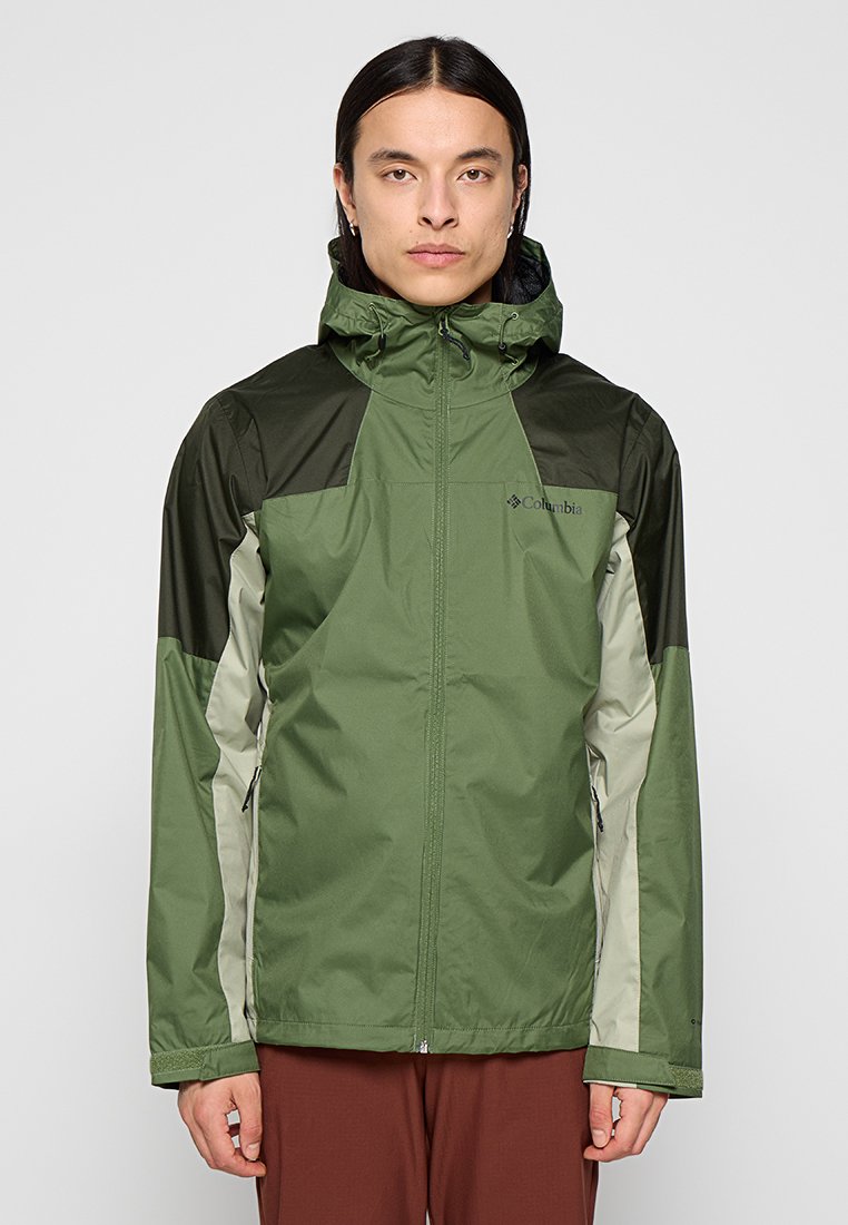 Veste imperméable verte avec capuche, présentant des panneaux d'épaule vert foncé et des inserts latéraux gris clair. Fermeture à glissière et poignets réglables.