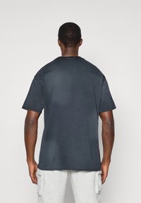 Σκούρο γκρι βαμβακερό μπλουζάκι κοντομάνικο, με κλασική λαιμόκοψη και άνετη γραμμή. Χωρίς ορατά σχέδια ή λογότυπα. Λείο υλικό.