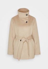 Beige jas gemaakt van zachte stof, met een hoge kraag, twee zwarte knopen en een ceintuur om te strikken. Heeft een losse, gestructureerde pasvorm.