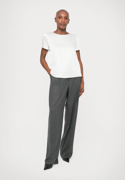 Λευκή κοντομάνικη μπλούζα συνδυασμένη με ψηλόμεσες γκρι κομμένες παντελόνες. Μαύρα γόβες με μυτερή μύτη ολοκληρώνουν την εμφάνιση. Απλός και σύγχρονος σχεδιασμός.