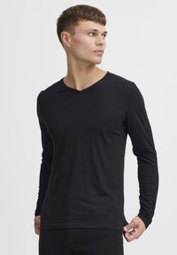 Cămașă neagră cu mâneci lungi și decolteu în V, fabricată dintr-un material moale. Dispune de o croială slim și o textură netedă, fără modele sau accente vizibile.