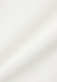 Tissu blanc texturé avec des plis diagonaux montrant un motif subtil en nid d'abeille et des ombres douces à travers la surface.
