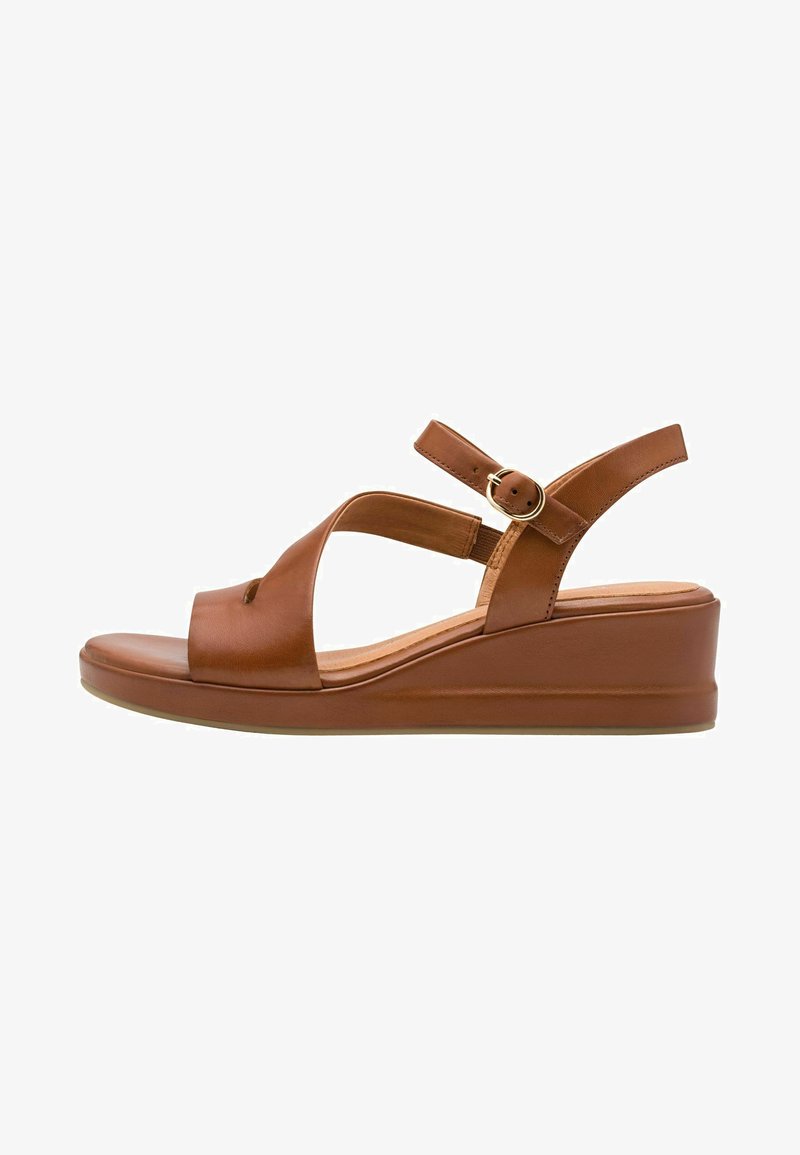 Sandales compensées en cuir marron avec design à lanières croisées, bride de cheville ajustable et semelle intérieure rembourrée pour le confort. Texture lisse, détails minimalistes.