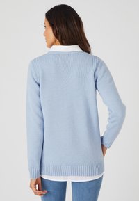 Cardigan en tricot bleu clair avec un ourlet et des poignets côtelés. Conçu avec une coupe décontractée et un motif texturé sur l'ensemble.