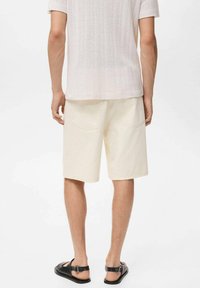 Ljusfärgade denimshorts med avslappnad passform, femficksdesign och synliga sömdetaljer, ihop med en strukturerad krämfärgad skjorta.
