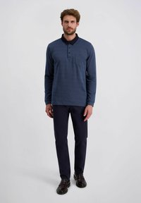 Blaues Langarm-Polohemd mit einem gerippten Kragen, einer Dreiknopf-Leiste und einer Brusttasche, kombiniert mit dunkelblauen Hosen und dunklen Schuhen.