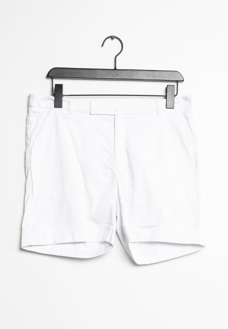 Bermudas de algodón blancas colgadas en una percha negra. Presentan bolsillos frontales y una textura suave y libre de arrugas con un diseño limpio y simple.