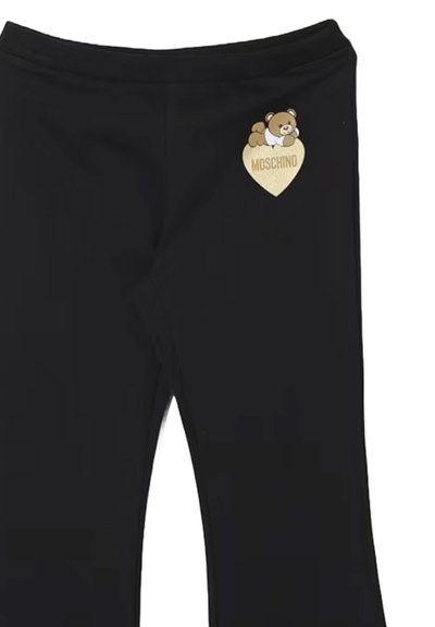 Pantaloni neri con un piccolo logo di un orsetto che si appoggia su un cuore d'oro con il testo "Moschino" sulla coscia sinistra superiore.