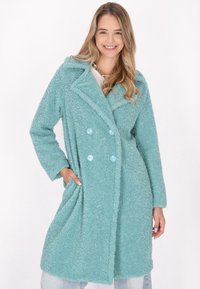 Cappotto in fleece turchese con design doppiopetto, rever a punte e bottoni blu. Presenta tasche laterali e una finitura testurizzata.