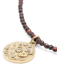 Collier pendentif en or avec un pendentif circulaire texturé, orné de strass et d'un motif de croissant de lune. Chaîne à perles de couleur brun foncé.