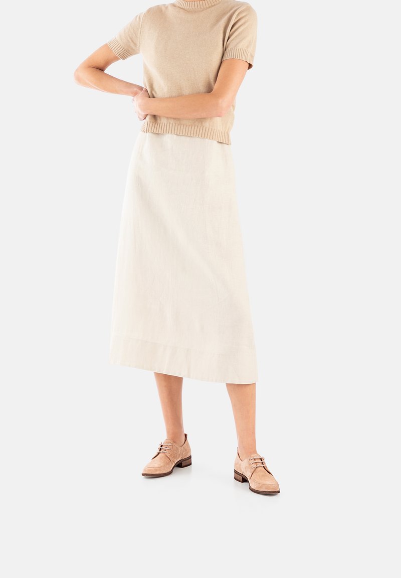 Beige gebreid T-shirt met korte mouwen, crèmekleurige linnen midi-jurk en lichtbruine suède veterschoenen met een klein hakje.