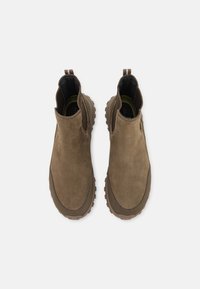 Botas de tobillo de ante marrón con suela de goma texturizada, que cuentan con paneles laterales elásticos y tiradores para ponérselas fácilmente. Acabado suave con punta redondeada.