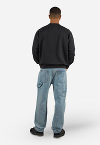 Sort sweatshirt med ribbet halsudskæring og manchetter, parret med lyseblå cargo jeans med flere lommer og en afslappet pasform.