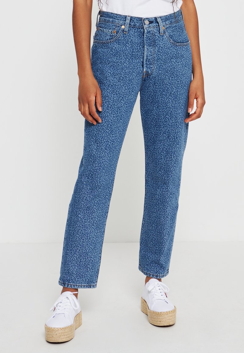 Högmidjade blå jeans med texturerat leopardmönster. Rakt ben-design, med bältesöglor och fem fickor. Kombineras med vita plattformsskor.