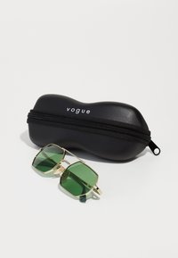 Ochelari de soare verzi, rectangulari, cu rame din metal aurit, așezate lângă un etui dur negru, marcă "vogue", cu închidere prin fermoar.