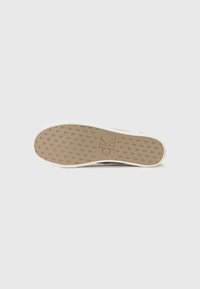 Semelle de sneaker Calvin Klein avec une surface en caoutchouc marron texturé, présentant une adhérence à motif et un logo embossé au centre.