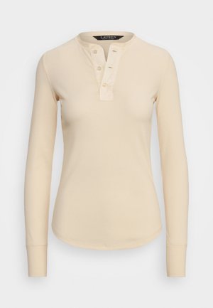 Camisa de mangas longas, estilo henley, em tecido canelado de bege claro com placket de três botões e bainha arredondada. Textura suave com design ajustado.