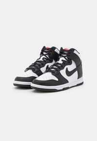 Sneaker alte in bianco e nero realizzate in pelle, con punta perforata, lacci neri e suola in gomma bianca con grip testurizzato.