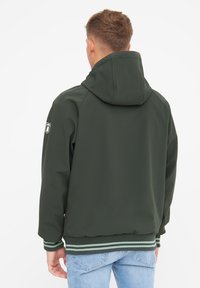 Dunkelgrüne Jacke mit Kapuze, gerippten Bündchen und Saum sowie einem Logo-Patch auf der linken Schulter. Strukturiertes Material, lässige Passform.