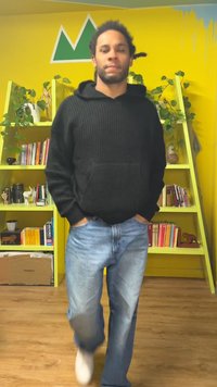 Mustast kootud kapuutsiga sviiter esikoti ja helesiniste teksadega. Ruumis kollased seinad ja rohelised riiulid koos taimede jaotusega.