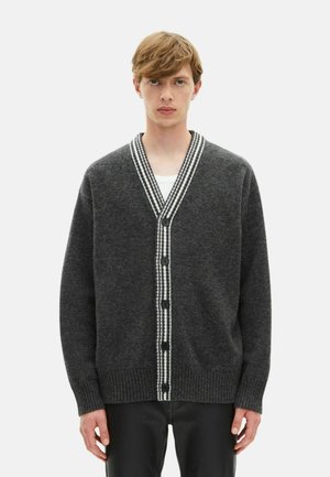 Dunkelgraue Wollkarte mit V-Ausschnitt, weiß gestreiftem Rand, sechs schwarzen Knöpfen und gerippten Bündchen und Saum. Weiche Textur, lässige Passform.