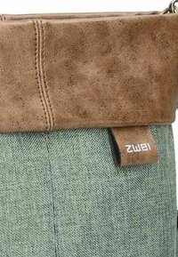 Top de imitación cuero marrón con un cuerpo de tela verde texturizada. Presenta una etiqueta con el nombre de la marca "Zwei" en el lateral. Diseño compacto.