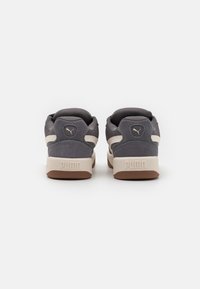 Grå ruskinds- og mesh sneakers med en beige sål. Har et karakteristisk logo på bagsiden og side-striber for ekstra designdetaljer.
