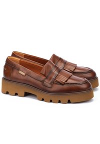 Mocasines de cuero marrón con detalle de flecos, cuello acolchado y una suela de goma gruesa. Parte superior texturizada y forro interior suave.