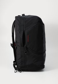 Svart reiseryggsekk med slitesterkt stoff, rektangulær form, justerbare stropper og ytterlomme med glidelås med "BOOTPACK"-etikett i rødt.