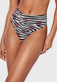 Parte inferior de bikini de talle alto en un estampado de cebra en blanco y negro, con lunares rojos. Textura suave y ajuste ceñido.