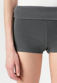 Grå ribbestrimlede shorts med en bred, foldet talje. Stoffet er mykt med en teksturert overflate, og de har en tettsittende design uten synlige mønstre.