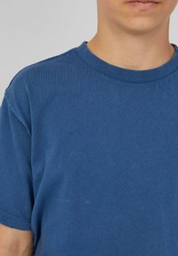 Blauwe T-shirt met korte mouwen van zacht katoen. Bevat een ronde hals en een gladde textuur met minimale stikdetails.