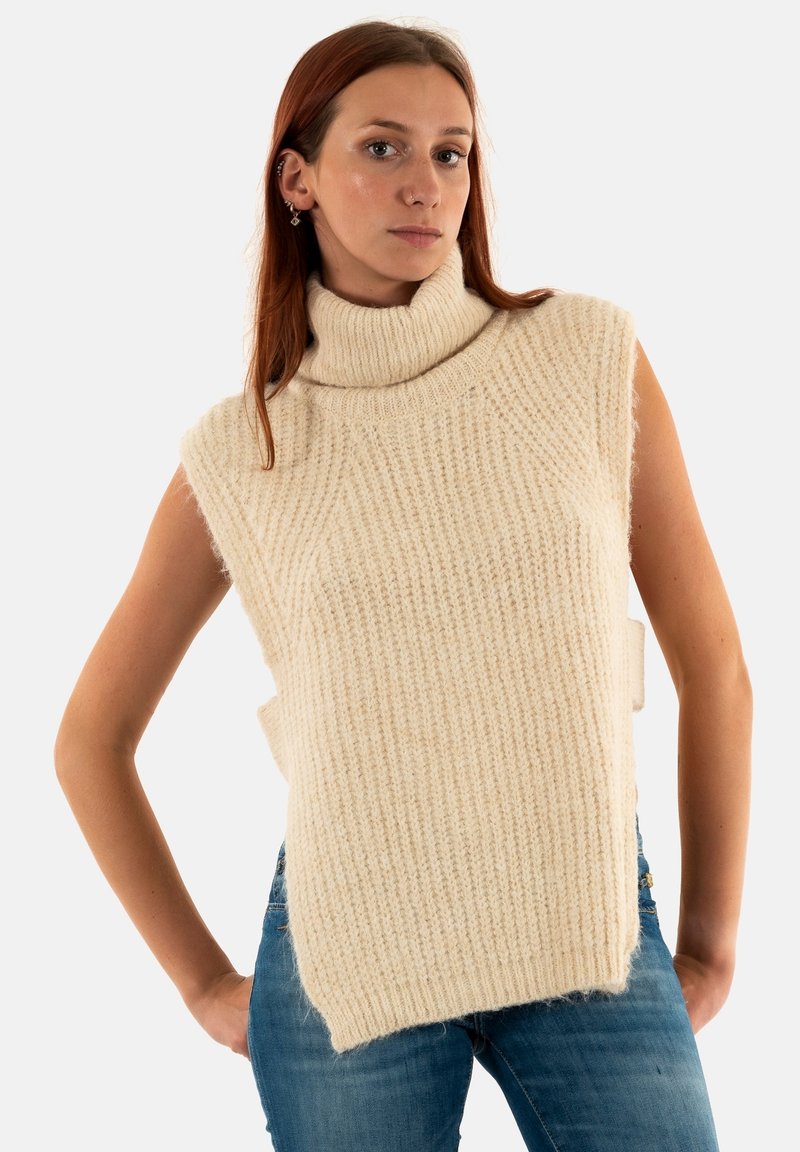 Suéter sin mangas de punto en color beige claro, que presenta un patrón texturizado y aberturas laterales. Tejido suave con un corte relajado.