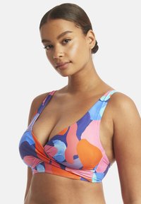 Top bikini colorato con forme astratte in rosa, arancio, blu e viola. Ha un design avvolgente con spalline larghe e scollatura a picco.
