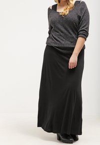 Gray, long-sleeve sweater with a relaxed fit, layered over a black maxi skirt. Black ankle boots complete the look. Smooth fabric textures.