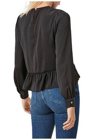 Blusa nera a maniche lunghe con orlo a peplum, texture sottile, chiusura a bottone sul retro e maniche tapered con dettagli a bottone.