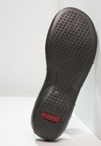 Czarna gumowa podeszwa buta z teksturowanym wzorem, z czerwoną logotypem "rieker" i nadrukiem rozmiaru 37. Gładkie krawędzie i lekka konstrukcja.