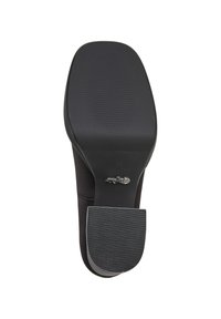 Semelle d'une chaussure noire avec un bout carré et un talon en caoutchouc texturé, affichant le logo de la marque près de la zone de la voûte plantaire.