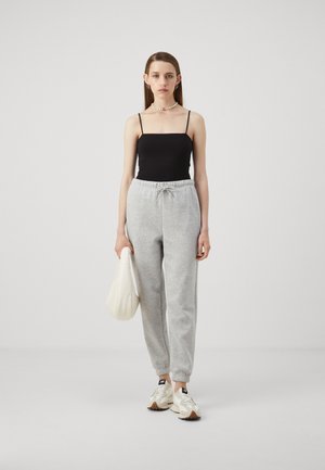 Black camisole top, grey drawstring sweatpants with elastic cuffs, white bag, and cream sneakers with beige accents. Simple, casual outfit.