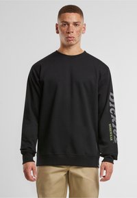 Fekete pamut pulóver hosszú ujjal. Elülső részén kerek nyak van, a jobb ujján a "DICKIES" logó szürke és zöld színekben látható. Sima tapintású.