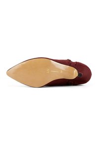 Scarpa in suede bordeaux con punta affilata e una suola beige liscia, caratterizzata da un tacco medio e una cucitura sottile lungo il bordino superiore.
